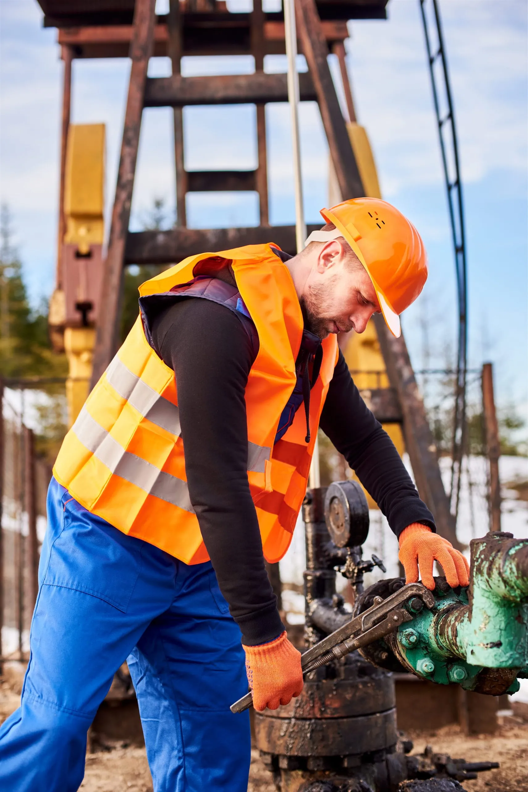Oil worker tightening nuts with industrial wrench in oil field